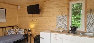 a bedroom with a bed and a sink and a television at Niezła Szopka domki nad jeziorem in Nowe Guty