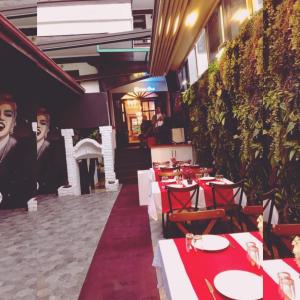 a restaurant with red tables and chairs and plants at Şirince otel in Amasya
