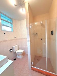 a bathroom with a toilet and a glass shower at Apto no centro - Praça Mini Golf - Sacada - Garagem - 300m do Mar - Térreo in Capão da Canoa