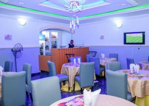 a dining room with tables and blue chairs and a man at Luxury Deluxe 1 Bed, 1 Bath in Otta
