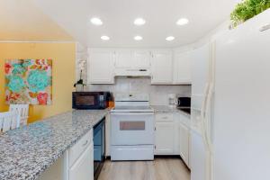 a kitchen with white cabinets and a white refrigerator at Oceanblock on One Twenty-Four in Ocean City