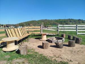 a group of benches and a fire pit in a field at Agroturystyka Przy Stajni in Zbylutów +13 photos