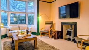 a living room with a fireplace and a tv at Family Home in Tywyn - Game and Cinema Rooms in Tywyn