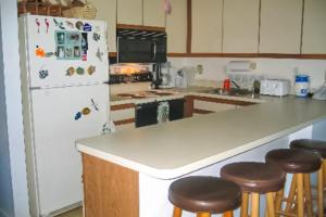 a kitchen with a white refrigerator and some bar stools at Bay Princess 103 in Ocean City