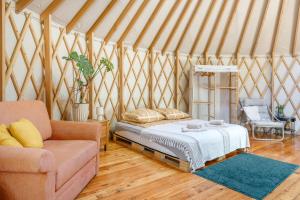 ein Schlafzimmer mit Bett und Sofa in einer Jurte in der Unterkunft Aloha Glamp - Całoroczny glamping nad rzeką z prywatną balią - Stok narciarski, góry, lasy, sauna in Zagórnik + 70 Fotos