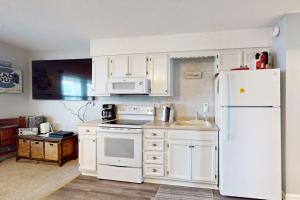 a kitchen with white cabinets and a white refrigerator at Sea Nymph in Ocean City