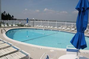a large swimming pool with chairs and blue umbrellas at Thunder Island 28A in Ocean City