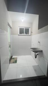 a white bathroom with a sink and a window at Casa Sol Nascente in Aquiraz