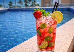 a drink with strawberries and mint next to a pool at Blue Hotel in João Pessoa