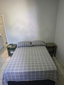 ein Schlafzimmer mit einem Bett und einer karierten Decke in der Unterkunft Kitnet NOMAD in Barão de Cocais