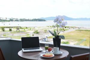 a laptop on a table with a view of the water at Hotel Kennedy in São José