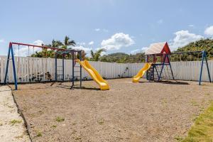 a playground with two swings and a slide at Hamilton @ Oceanpointe a serene 2bed 2 bath Villa in Lucea