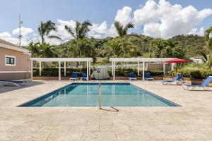 a swimming pool with chairs and a umbrella at Hamilton @ Oceanpointe a serene 2bed 2 bath Villa in Lucea