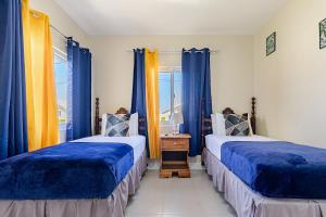 two beds in a room with blue and yellow curtains at Hamilton @ Oceanpointe a serene 2bed 2 bath Villa in Lucea +63 photos