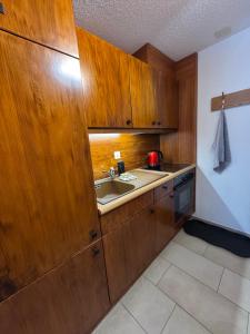 a kitchen with wooden cabinets and a sink at Cozy Studio with Wellness in Goms in Blitzingen