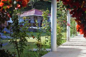 a house with a porch and a garden with flowers at Hostería en Chachimbiro - Ariq in Hacienda San Francisco