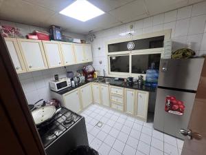 a small kitchen with a refrigerator and a sink at 1 BHK Flat in Sharjah