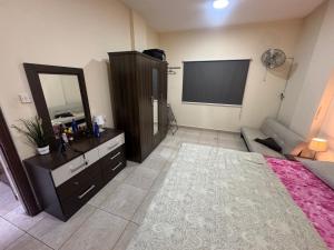 a bedroom with a mirror and a dresser and a television at 1 BHK Flat in Sharjah