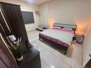 a bedroom with a large bed with a pink blanket at 1 BHK Flat in Sharjah
