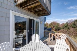 a deck with white chairs and a balcony at 4218 - The Scotts' SandBar in Duck