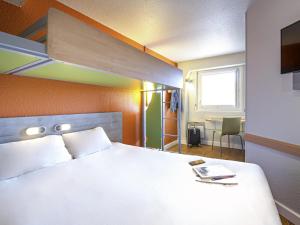 a bedroom with a bed and a table and a window at ibis budget Vienne Sud in Vienne