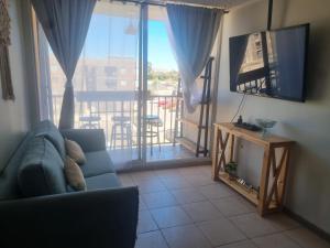a living room with a couch and a television and a balcony at Dpto santa rosa in Ovalle