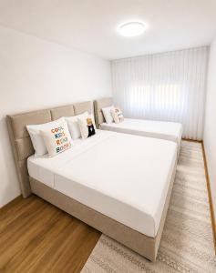 two beds in a bedroom with white walls and wood floors at Sara Luxe Family in Konjic