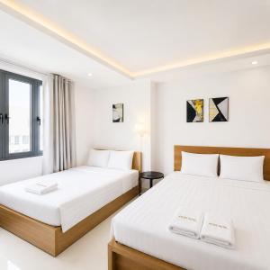 two beds in a room with white walls at Atusy Hotel in Ho Chi Minh City