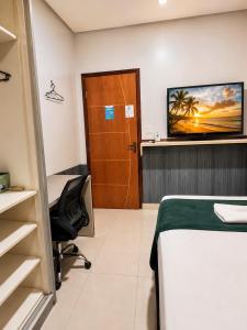 a room with a bed and a desk and a chair at Quarto 6 econômico próximo do aeroporto ar condicionado cama de casal in Marabá
