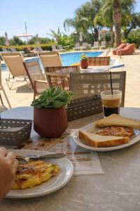 a table with two plates of pizza and a drink at Sunflower Apartments & Studios in Laganas