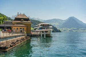 a boat is docked next to a building on the water at BASEKAMP Prime I Friends I Lake I Mountains I Luzern in Küssnacht