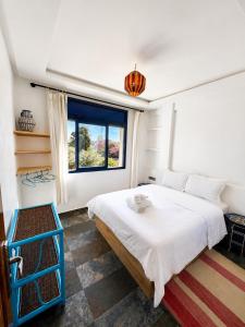 a bedroom with a large white bed and a window at La coline vue sur mer Uniquement les familles in Oualidia