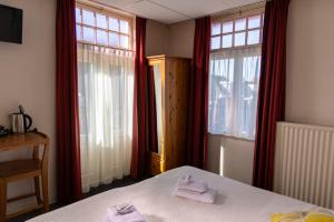 a bedroom with two towels on a bed with windows at HCR Teernstra in Balk