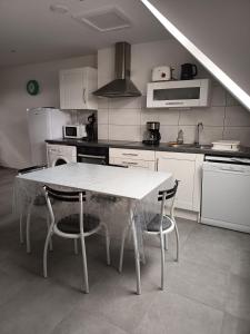 a kitchen with a white table and chairs in it at Charmant T2 Cosy - Sous les toits in Luxeuil-les-Bains