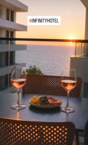 two glasses of wine and a plate of food on a table at Hotel Infinity Shëngjin in Lezhë