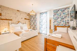 a white bedroom with two beds and a kitchen at Alaçatı Limonaia Hotel in Alaçatı