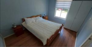a bedroom with a bed with white sheets and a window at Sendero de Luna in Valdivia