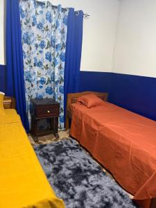 a bedroom with two beds and a table and blue walls at Logis Baobab in Morondava