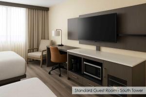 a hotel room with a desk with a flat screen tv at Plaza Suites On International Drive Near Universal Epic in Orlando