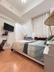a bedroom with a bed and a flat screen tv at Lofts aconchegantes no Palácio Quitandinha in Petrópolis +76 photos