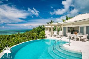 a swimming pool in front of a house with the ocean at Turtle Beach 5BR Snorkeling Kayaks & Family Entertainment in Providenciales