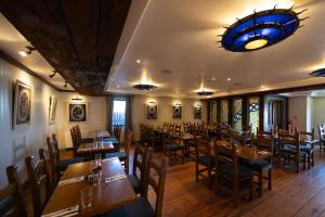 a restaurant with wooden tables and chairs and a chandelier at Aran Islands Hotel in Kilronan