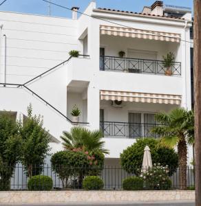 a white building with plants and a fence at SunsetApartment in Siviri