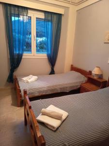 a room with two beds and a window with blue curtains at Akratas Brothers House in Akrata