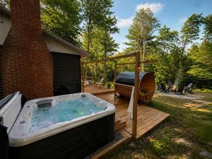 a hot tub on a deck next to a house at Sauna Forest Escape & Relaxation - Chalet Orman in Brownsburg