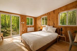 a bedroom with wooden walls and a bed and windows at Sauna Forest Escape & Relaxation - Chalet Orman in Brownsburg