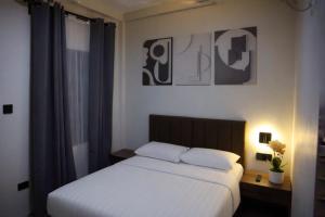 a bedroom with a white bed and a night stand with a lamp at Locale District Boutique Hotel in Quezon +28 photos