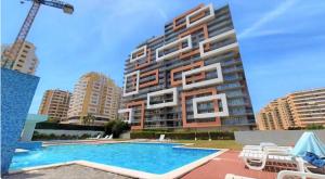 a large building with a swimming pool in front of it at The Surf - Rocha Tower in Portimão