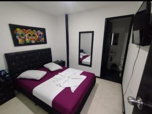 a bedroom with a bed with purple and white sheets at Hospedaje Luna Dorada in Manizales