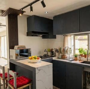 a kitchen with black cabinets and a bowl of fruit on a counter at Villa renacer in Baní